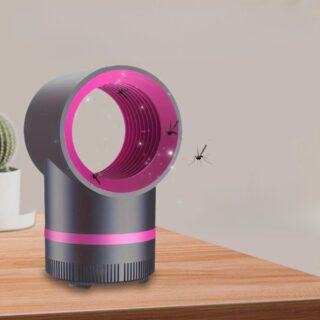 Piège à moustique noir avec tête circulaire rose, posé sur une table en bois.